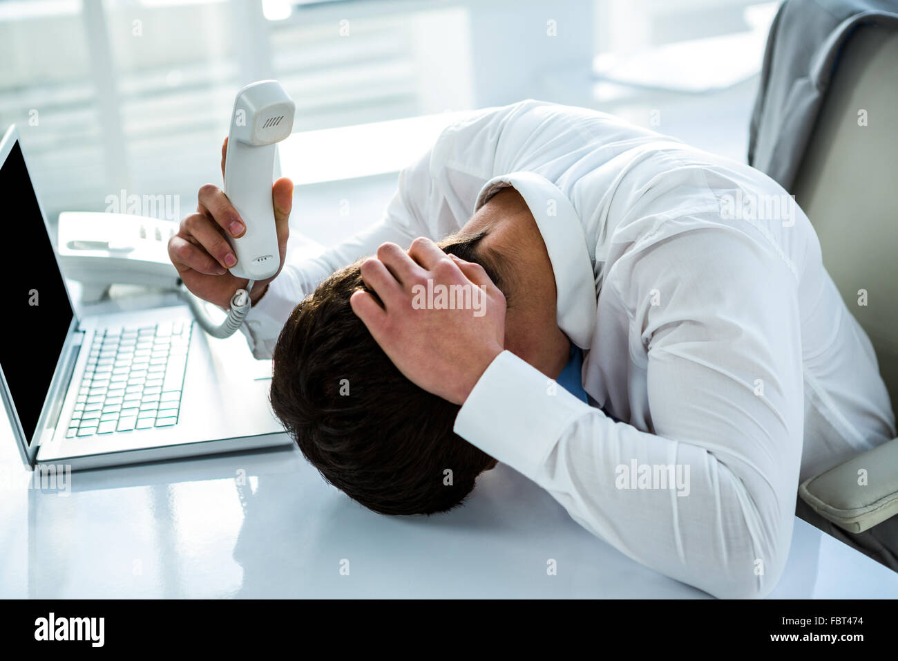 Overwhelmed asian businessman answering the phone Stock Photo