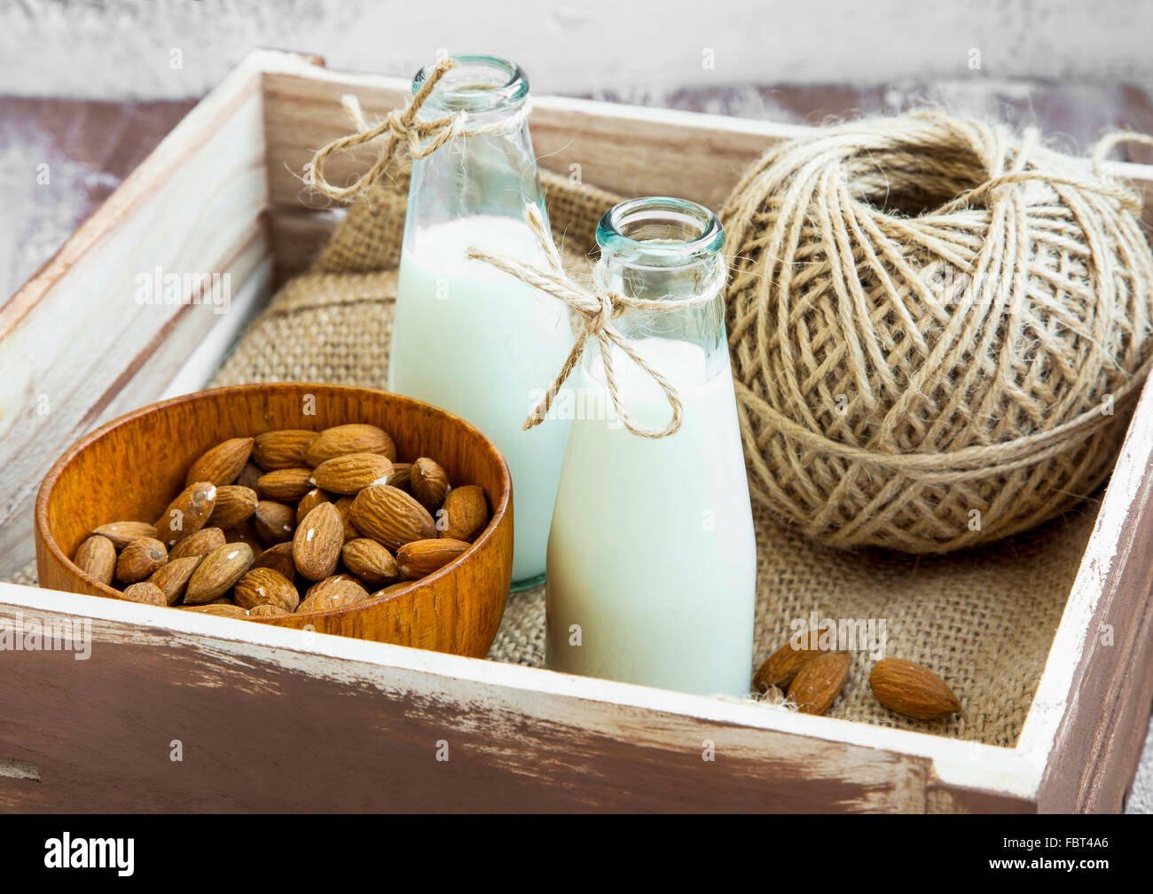 Almond milk in bottles with almond nuts bowl in wooden box Stock Photo