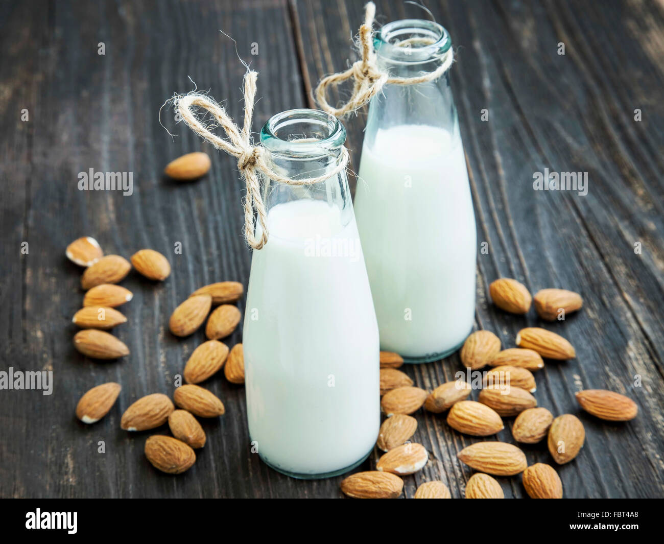 Almond milk in bottles with almond nuts on wooden background Stock Photo