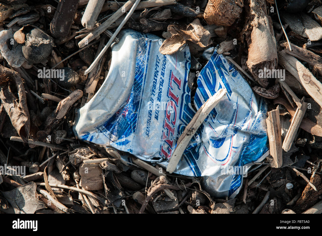 Crushed and weathered beer can viewed close-up with other beach debris. Stock Photo
