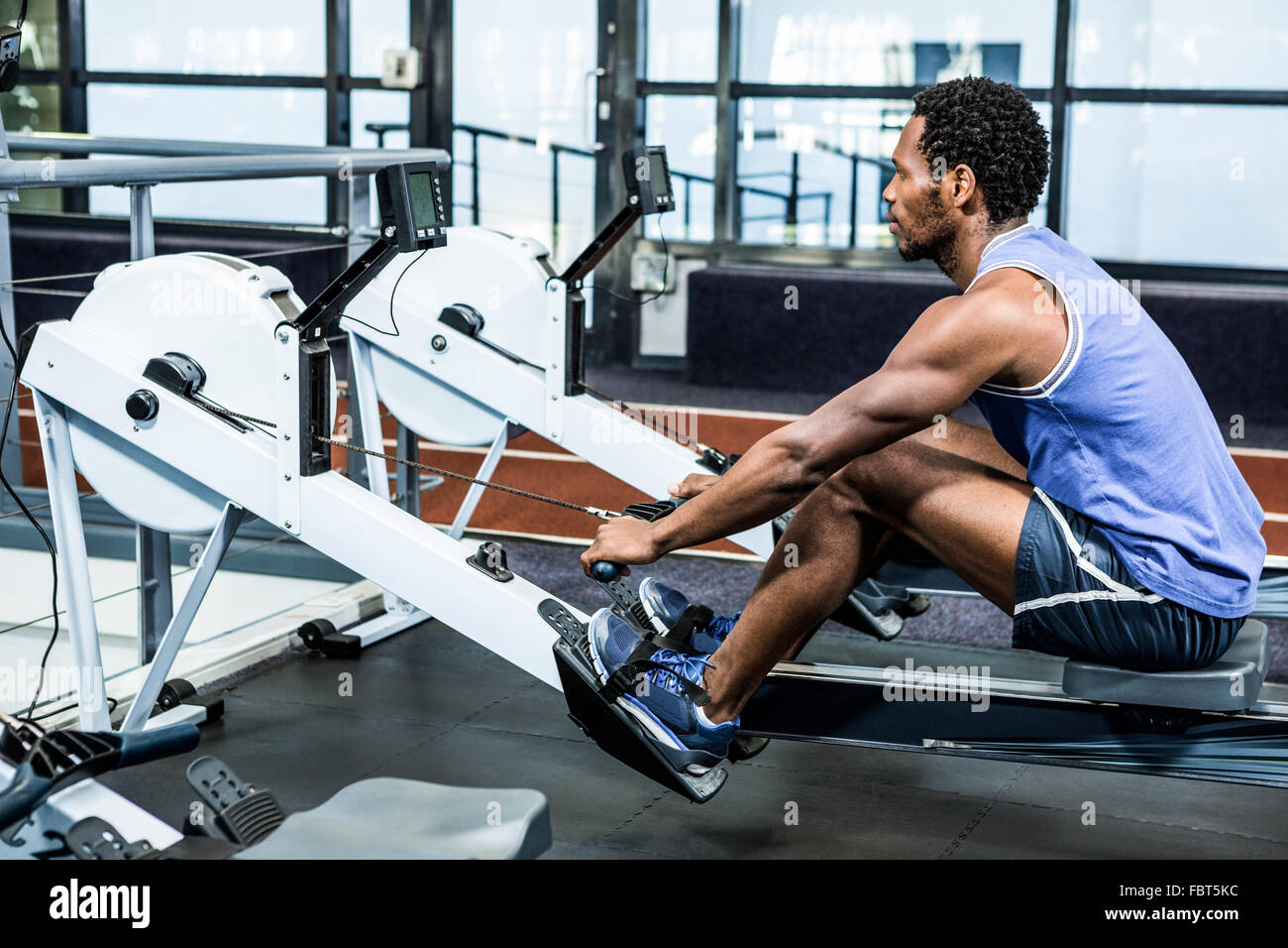 Muscular man using rowing machine Stock Photo