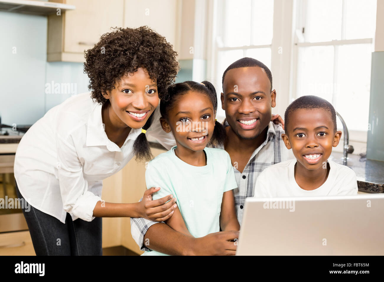 Happy family using laptop in the kitchen Stock Photo - Alamy