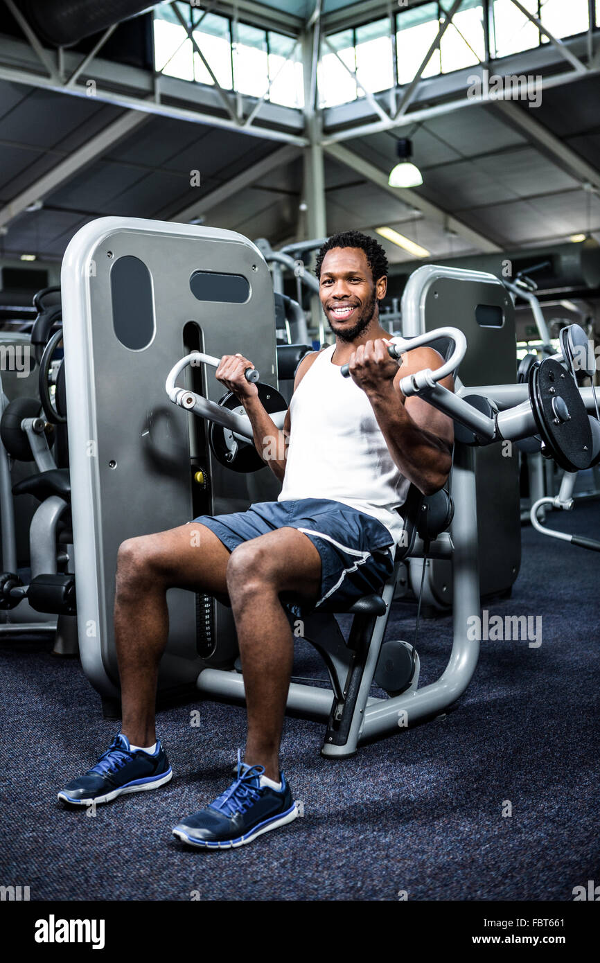 Smiling muscular man using exercise machine Stock Photo