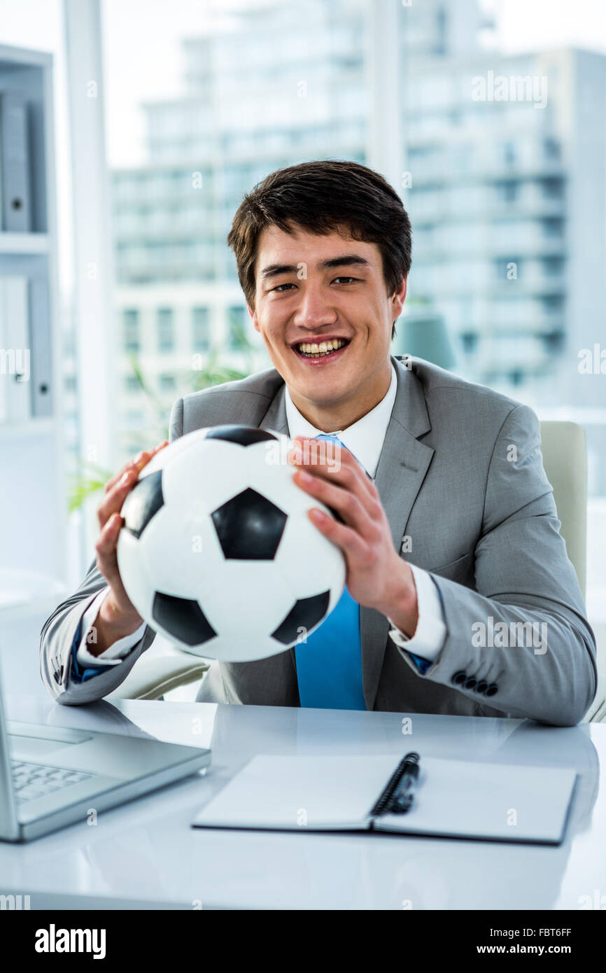 Asian businessman holding soccer ball with thumps up Stock Photo