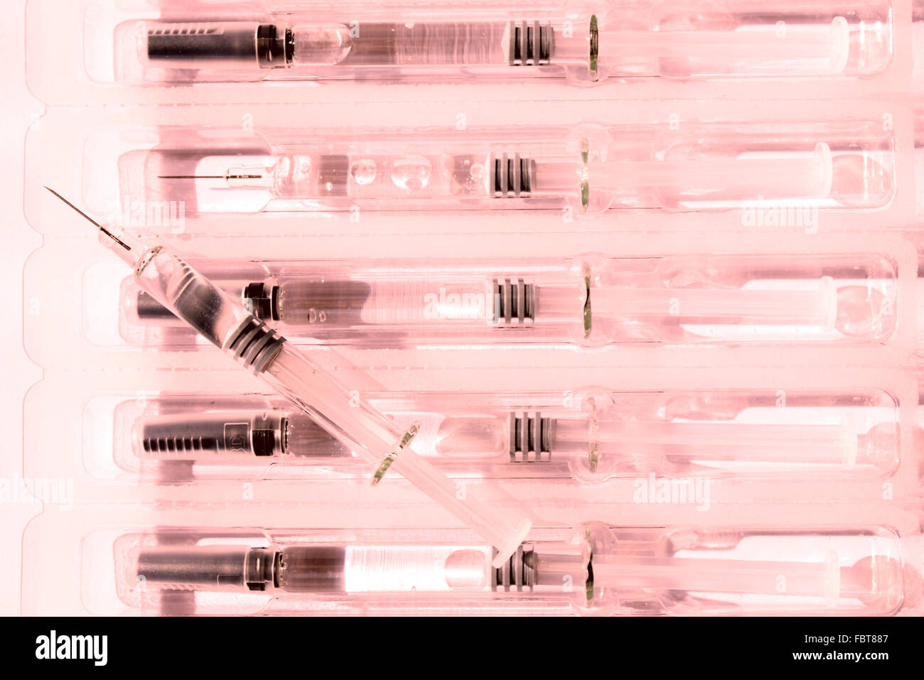 many syringes in a package in pink light Stock Photo