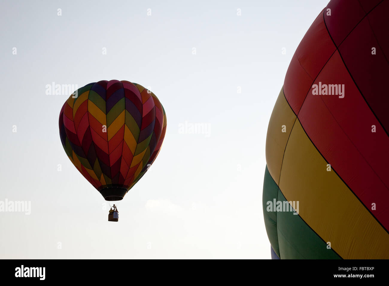 Hot air balloon rising and passing by a second balloon still on the ground Stock Photo
