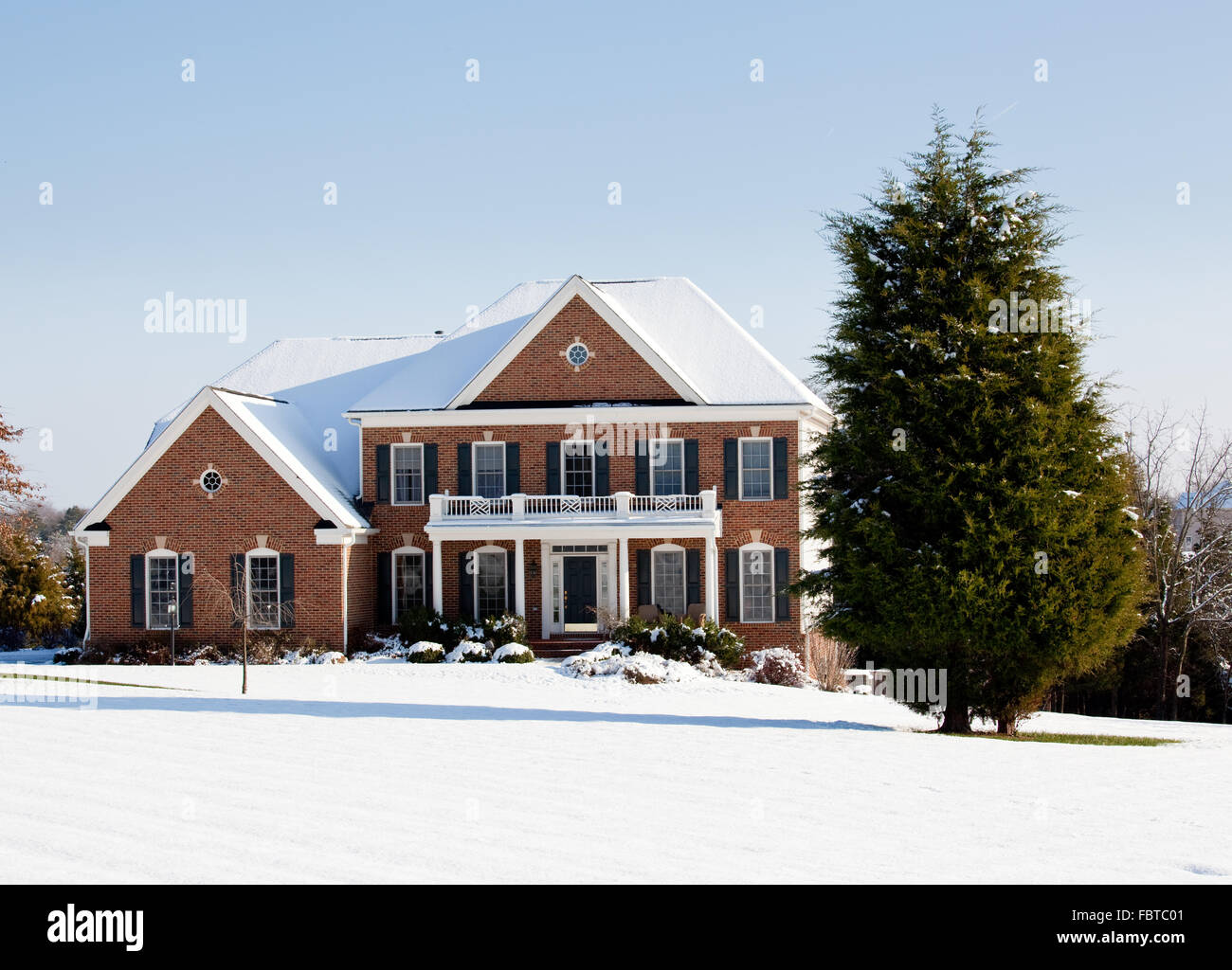 Modern home in a snowy setting with a conifer in the foreground Stock Photo