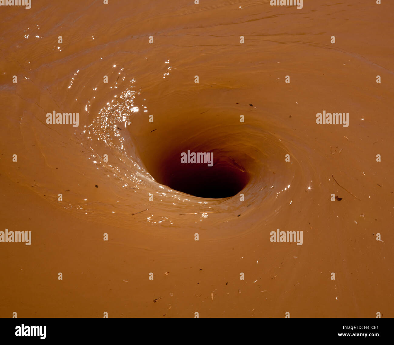 Deep brown flood water in river swirling into a whirlpool Stock Photo
