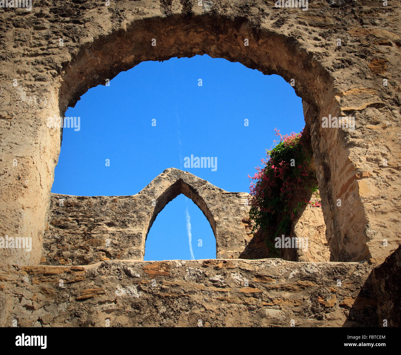 View of an old arch in San Juan Mission in Texas with modern jet trail in sky Stock Photo