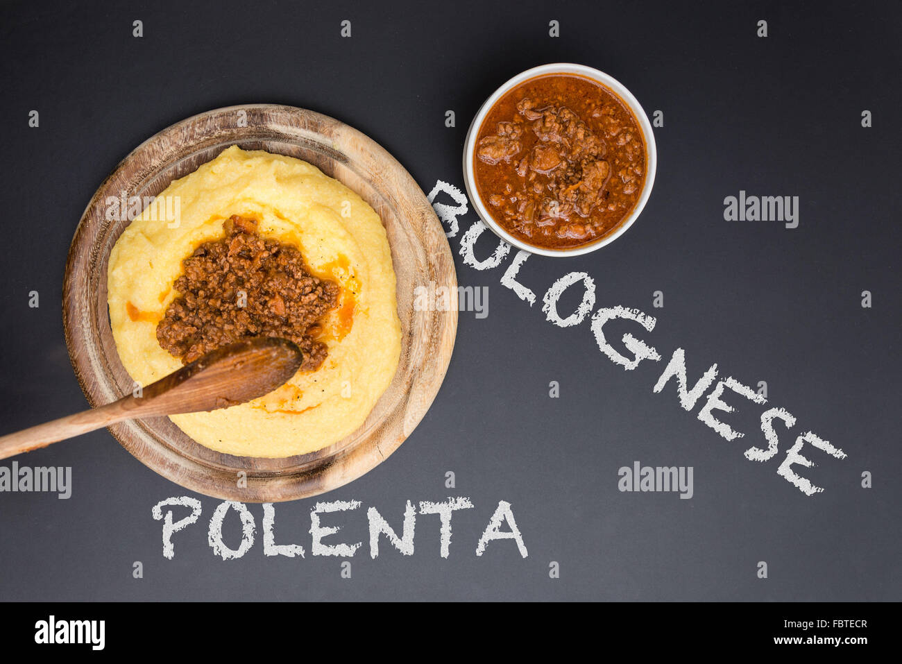 A dish of Polenta with bolognese soup (aka Ragout) standing on a black-board. Bolognese and polenta on the blackboard Stock Photo