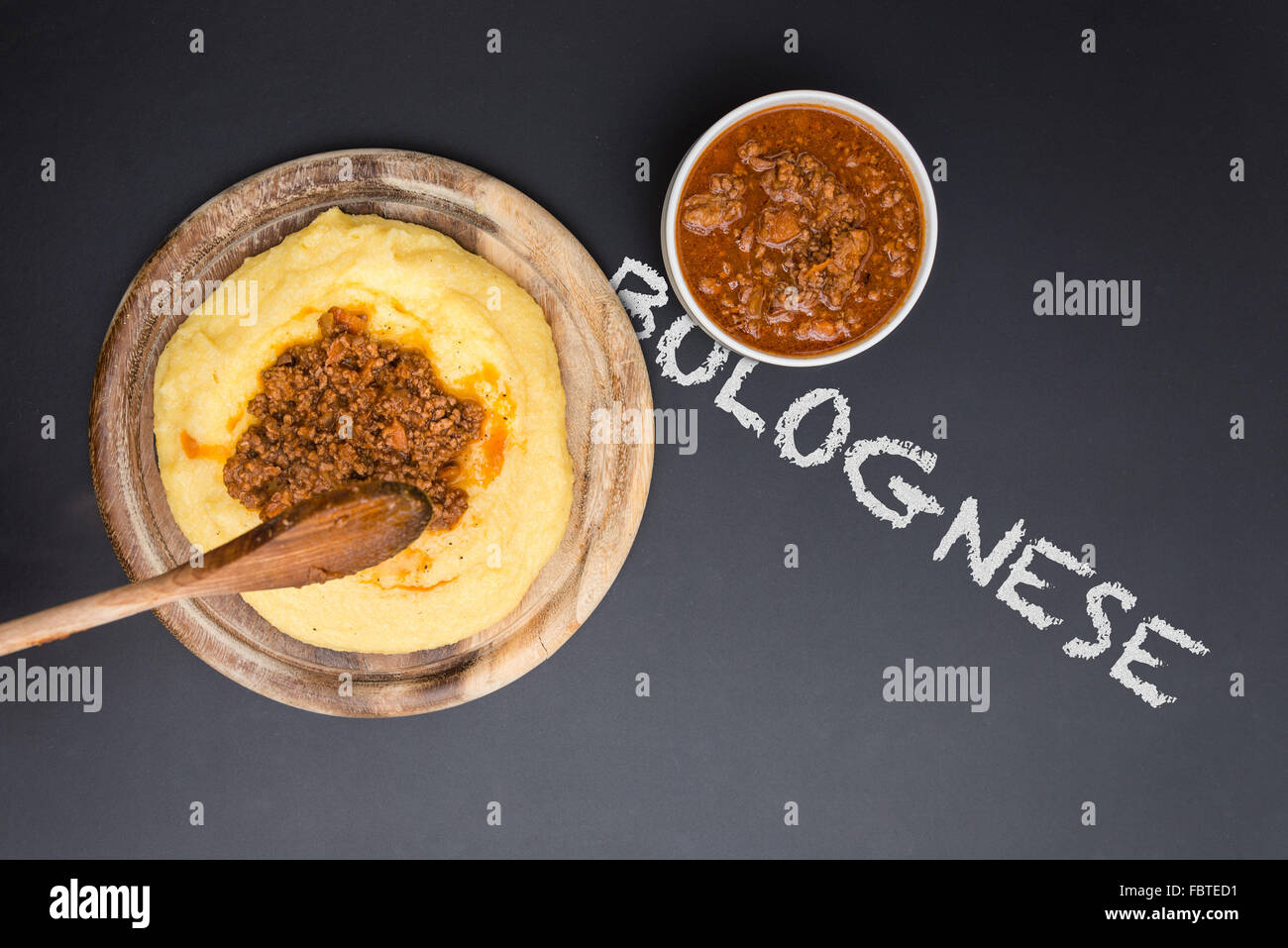 A dish of Polenta with bolognese soup (aka Ragu) standing on a black-board. Bolognese on the blackboard Stock Photo