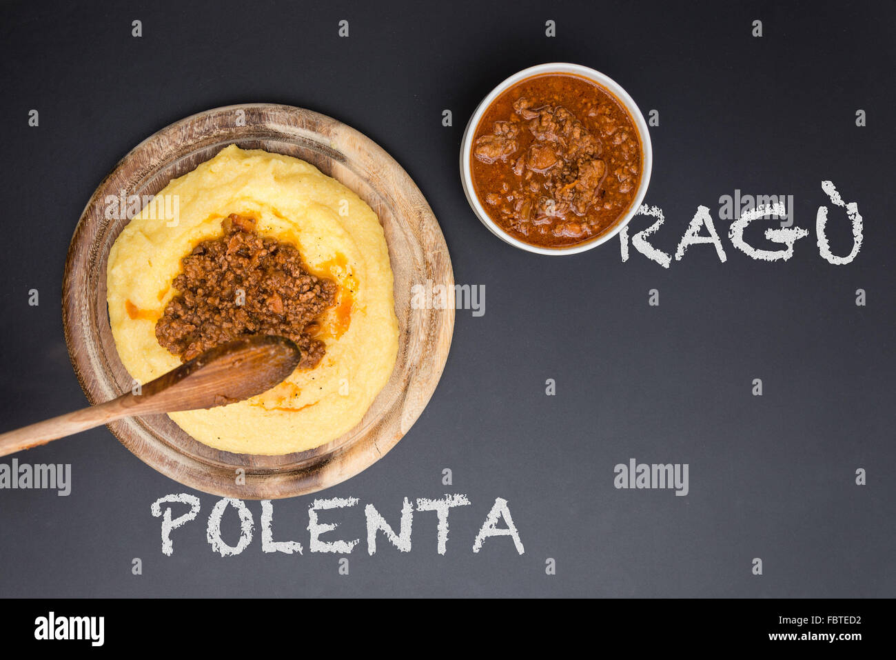 A dish of Polenta with bolognese soup (aka Ragu) standing on a black-board. Ragu and polenta on the blackboard Stock Photo
