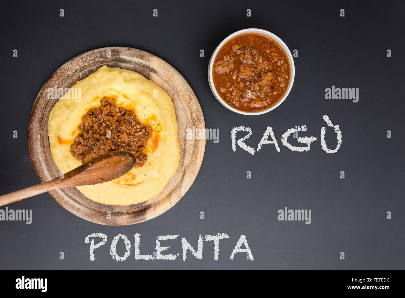 A dish of Polenta with bolognese soup (aka Ragout) standing on a black-board. Ragu and polenta on the blackboard Stock Photo