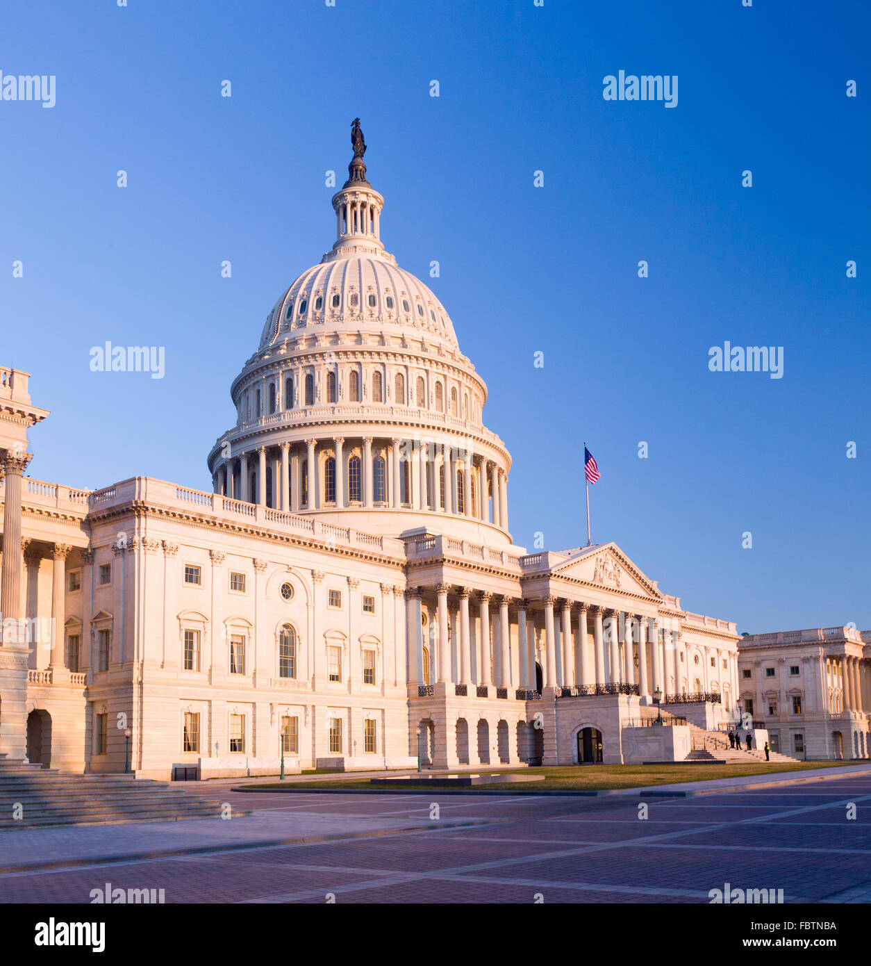 Rising sun illuminates the front of the Capitol building in DC Stock