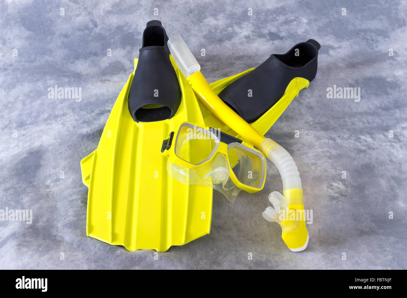 yellow snorkel mask and fins snorkeling gear isolated against gray background Stock Photo