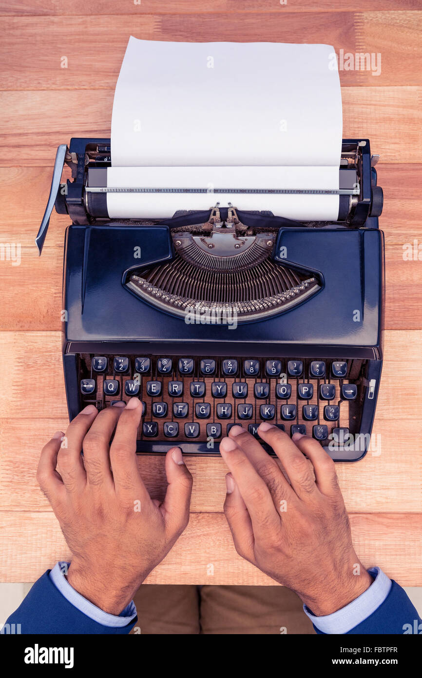 Businessman typing on typewriter at wooden desk Stock Photo