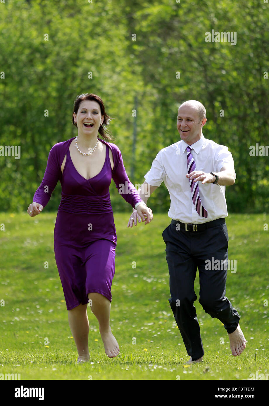 a man and a woman running in a meadow Stock Photo