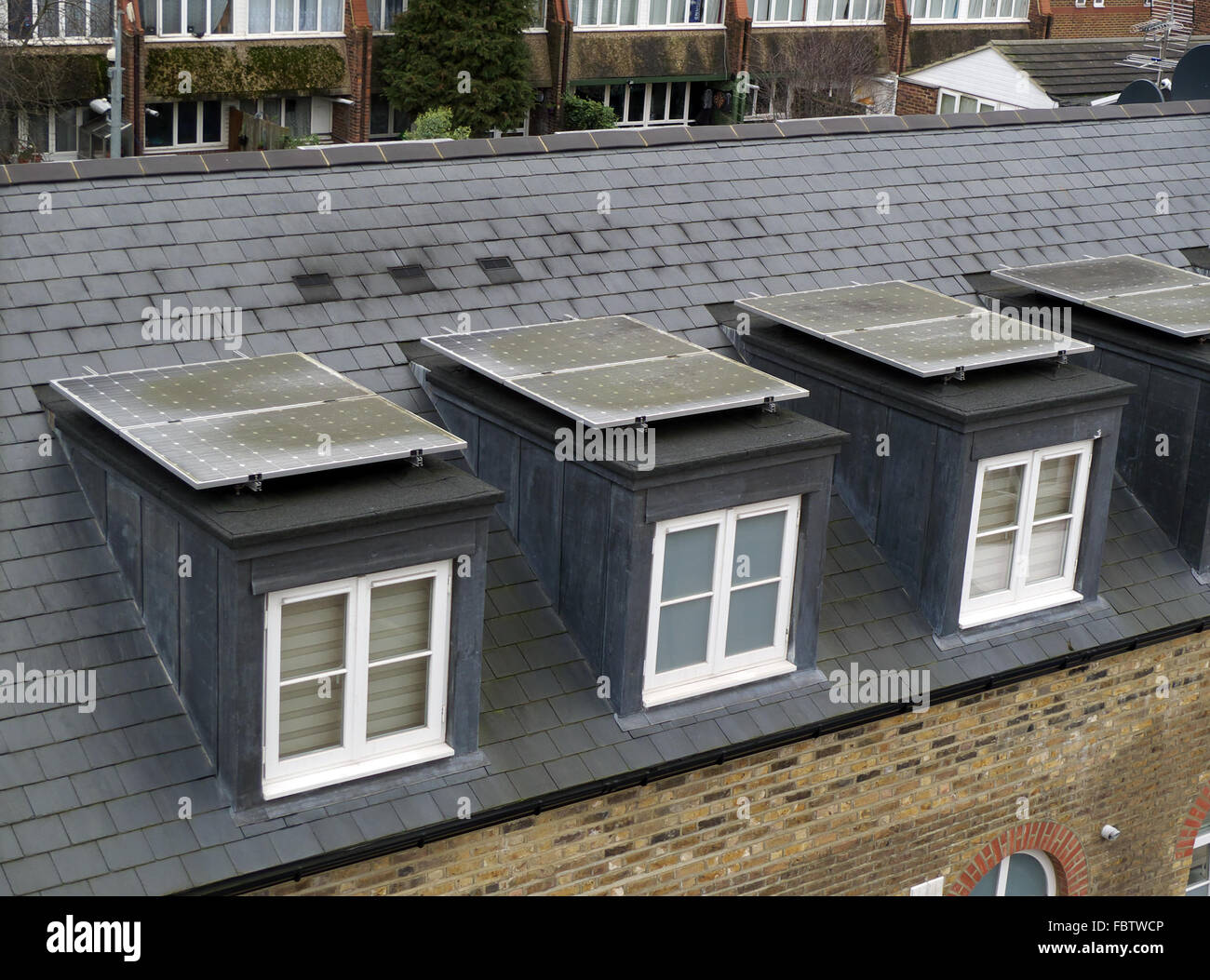 Dirty solar panels on dormer window rooftops, Brentford, London, UK. In need of cleaning. Stock Photo