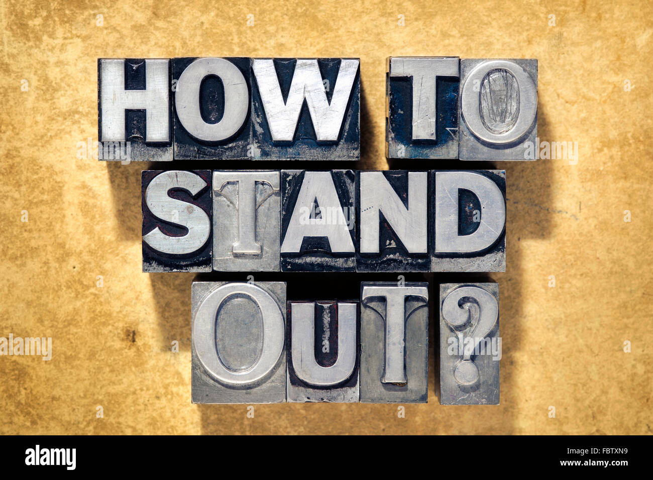 how to stand out question made from metallic letterpress type on grunge cardboard background Stock Photo