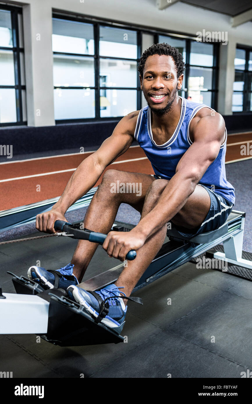 Muscular man using rowing machine Stock Photo