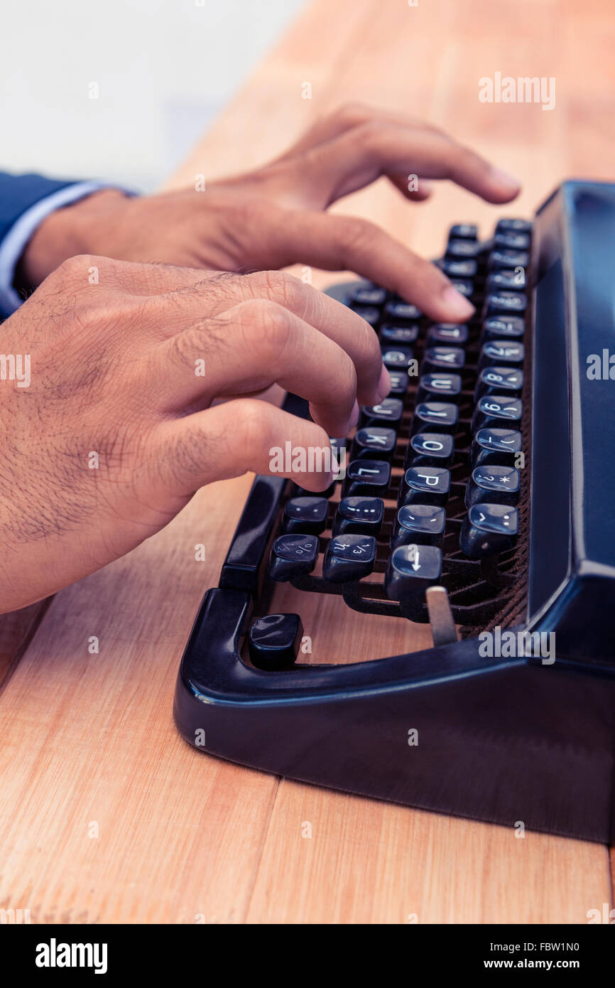 Businessman typing on typewriter at wooden desk Stock Photo
