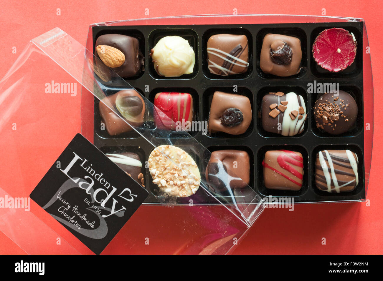 Opened box of Linden Lady luxury handmade chocolates showing contents set on red background Stock Photo