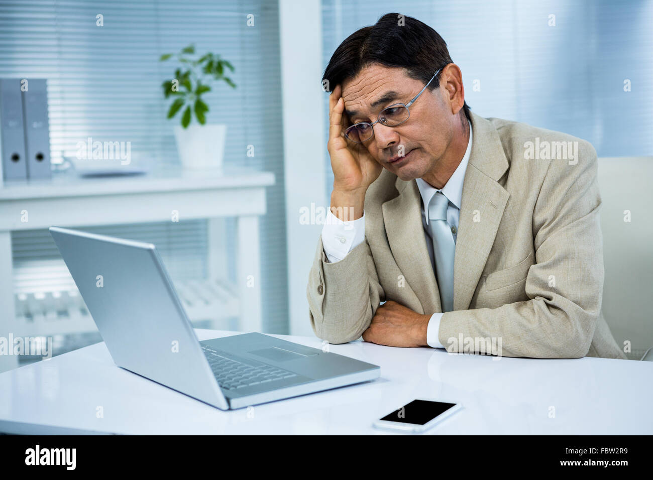 Undecided businessman looks his computer Stock Photo