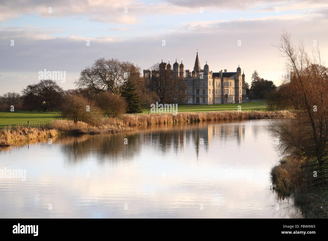 A dawn view of Burghley House across the Capability Brown design lake and landscape. Stock Photo