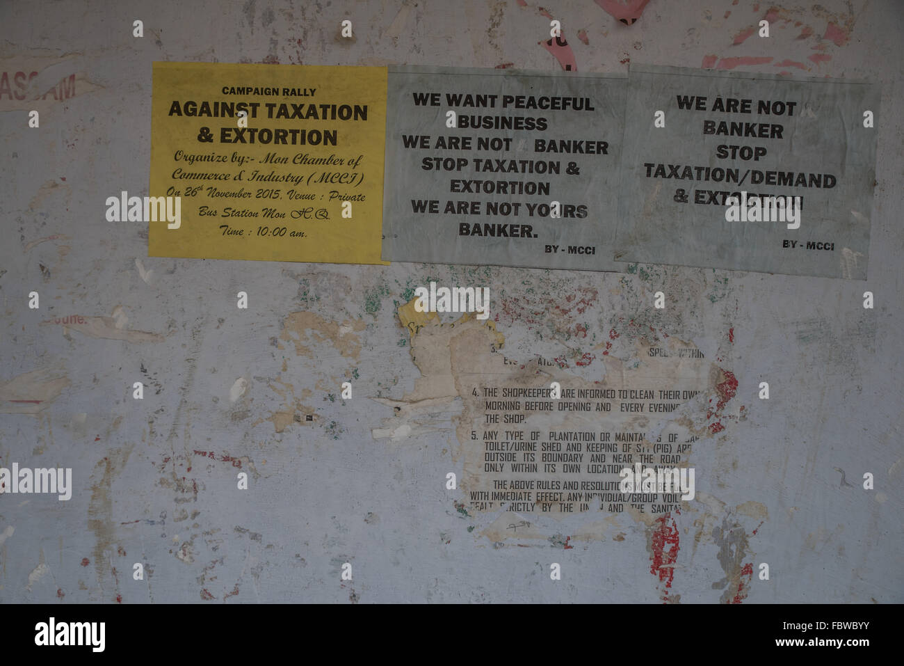 Against taxation and Extortion. Damaged and eroding protest posters on boarded up shop fronts in Mon, Nagaland, India. Stock Photo