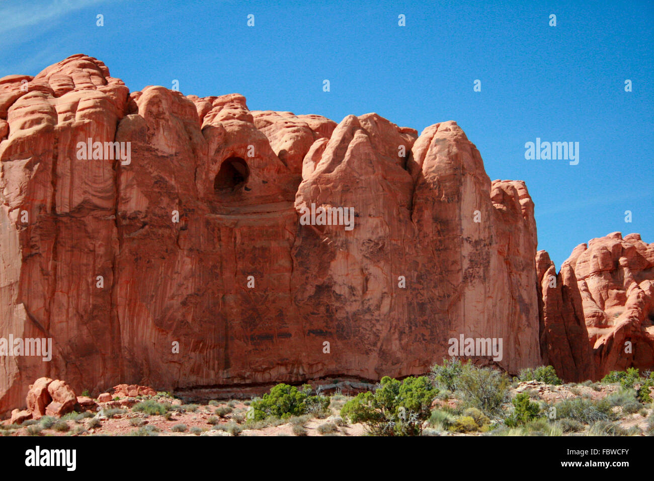 A red rock formation with a cave carved out of Entrada Sandstone in Arches National Park near Moab Utah. Stock Photo