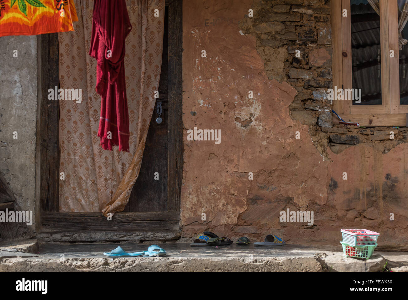 Exposed brickwork and flaking plaster. Signs of a neglected house facade. A study in umber hues. Sangti Arunachal Pradesh INDIA. Stock Photo