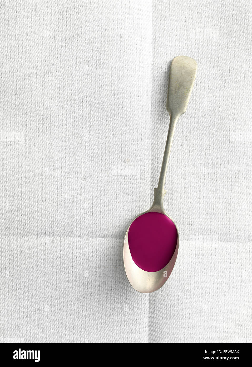 old spoon with liquid on linen table cloth Stock Photo