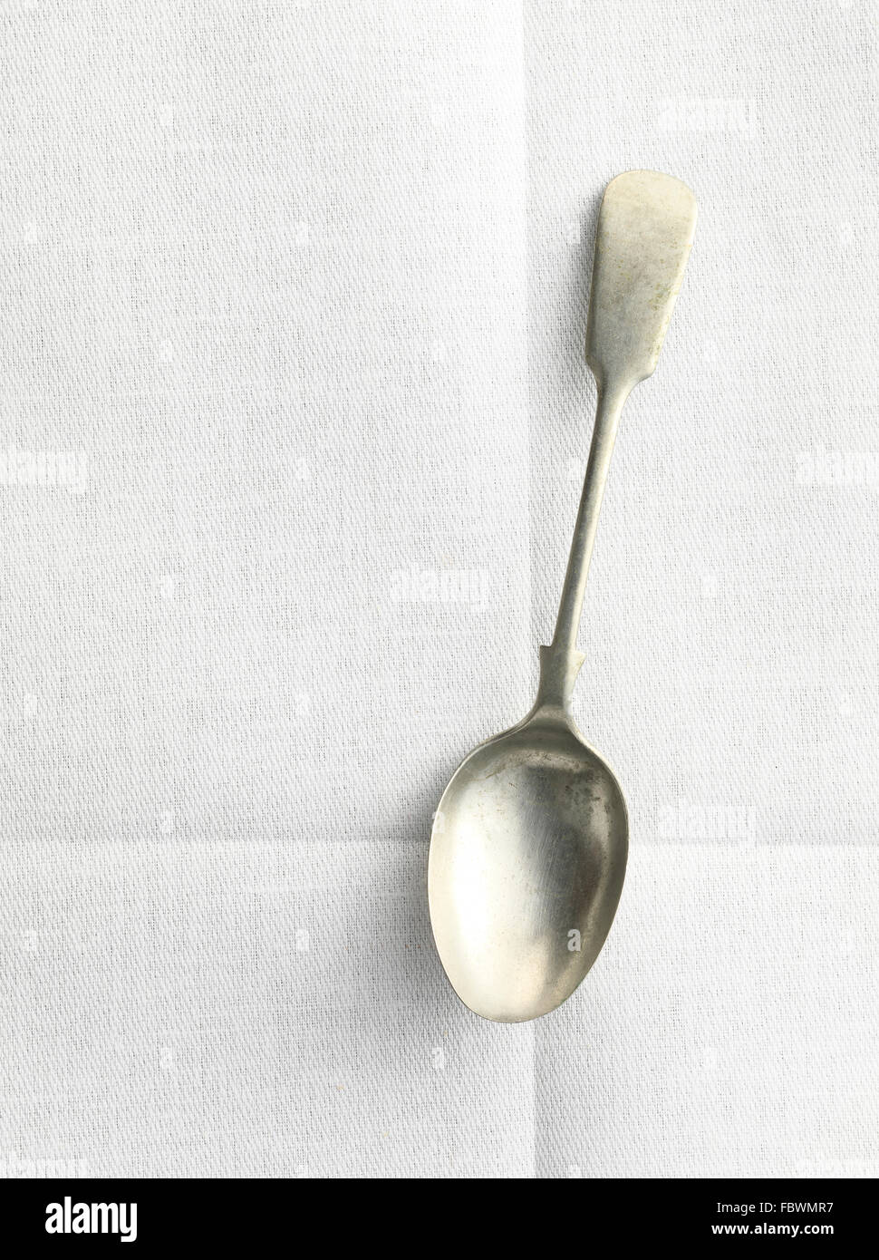 old spoon on linen table cloth with creases Stock Photo