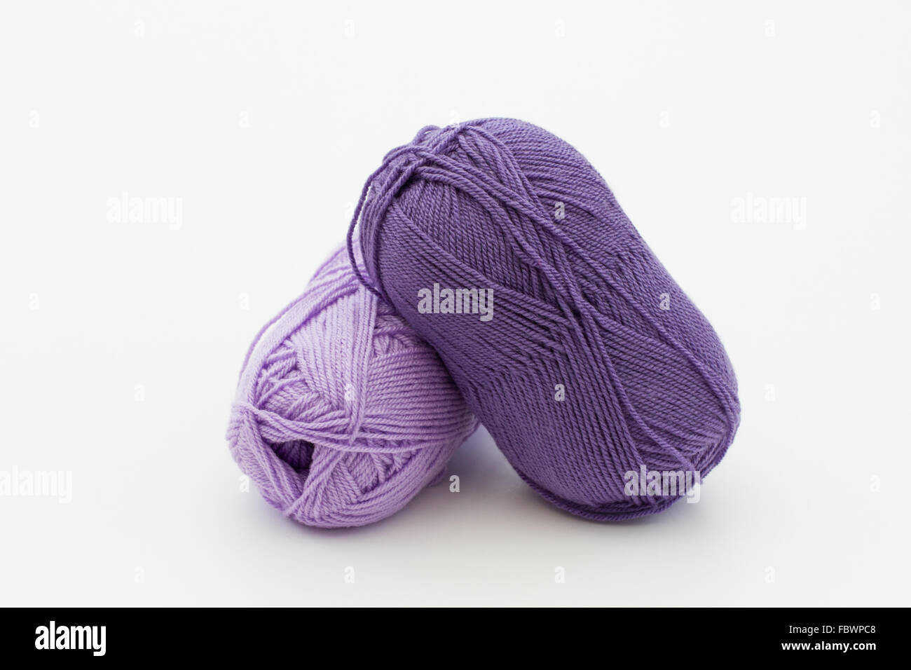 Two balls of wool in a purple color on an isolated white background. Stock Photo