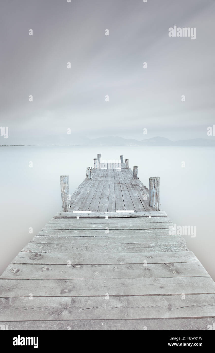 Wooden pier in a cloudy and foggy mood. A long exposure photography taken in autumn. Stock Photo
