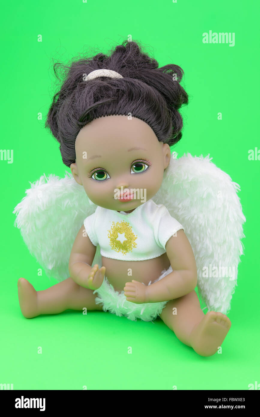 black, tan, skin tone doll in angel suit, white wings, girl, green background Stock Photo