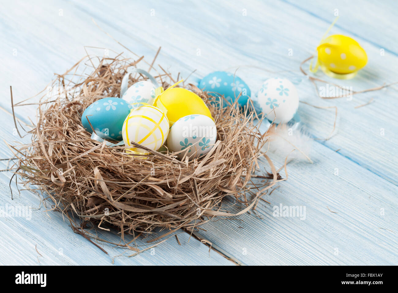 Easter card with colorful eggs in nest over wooden table. Top view with ...
