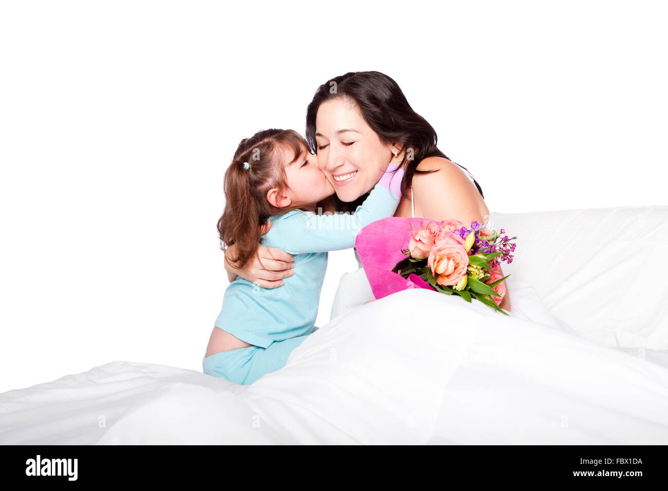Child gives flowers and kiss to mom in bed Stock Photo