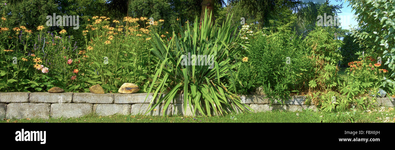 stonewall and flourishing flowerbed at summer Stock Photo