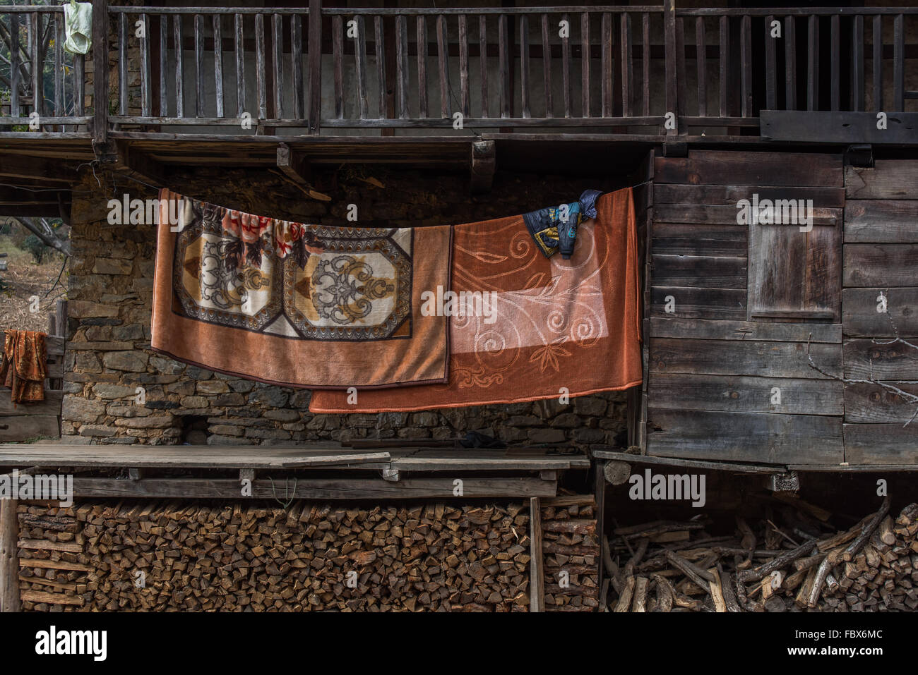 Thick warm blankets hung to air outside a traditional wooden house front in the village of Sangti, Arunachal Pradesh, INDIA. Stock Photo