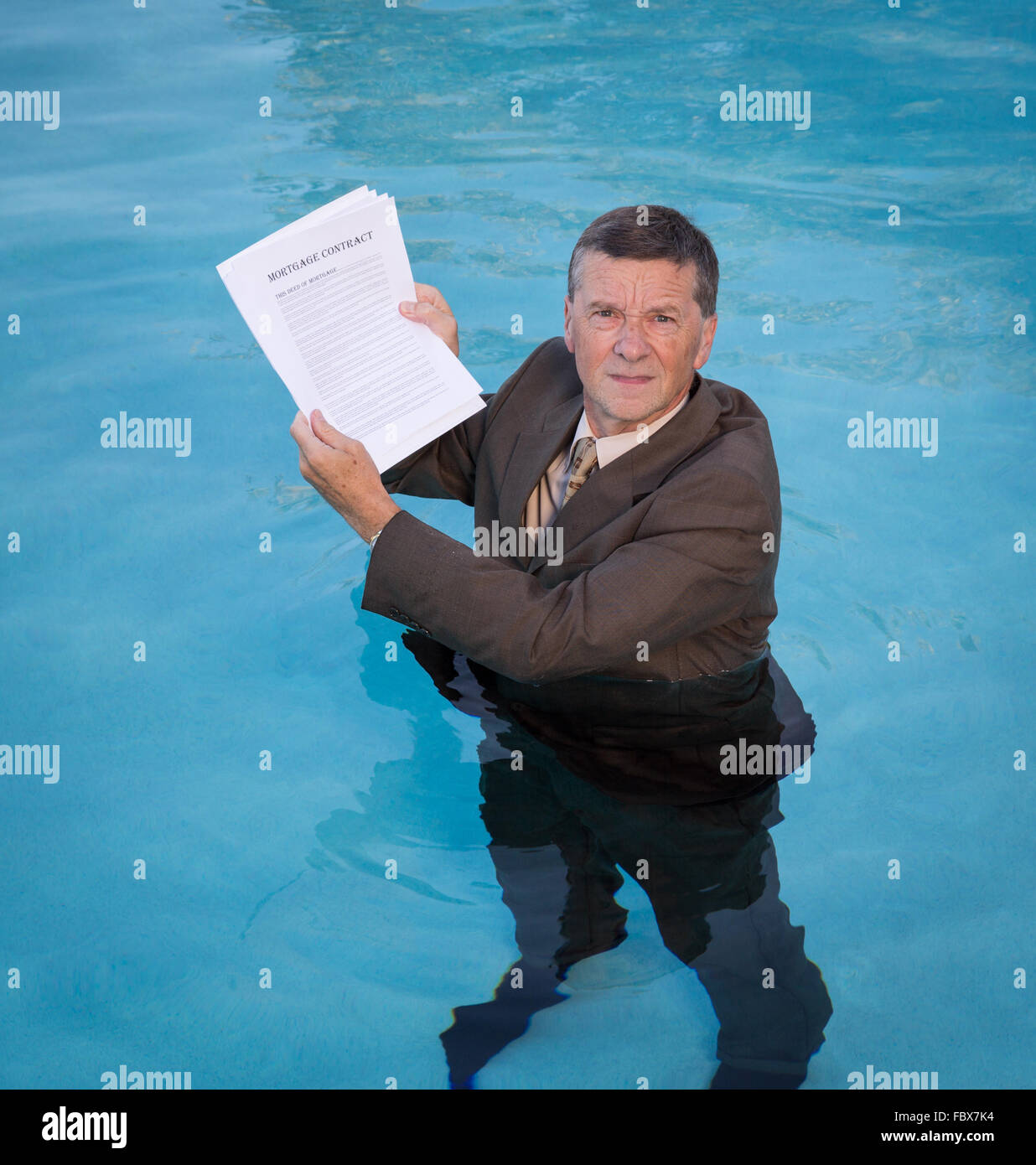 Senior man holding mortgage loan document in water Stock Photo