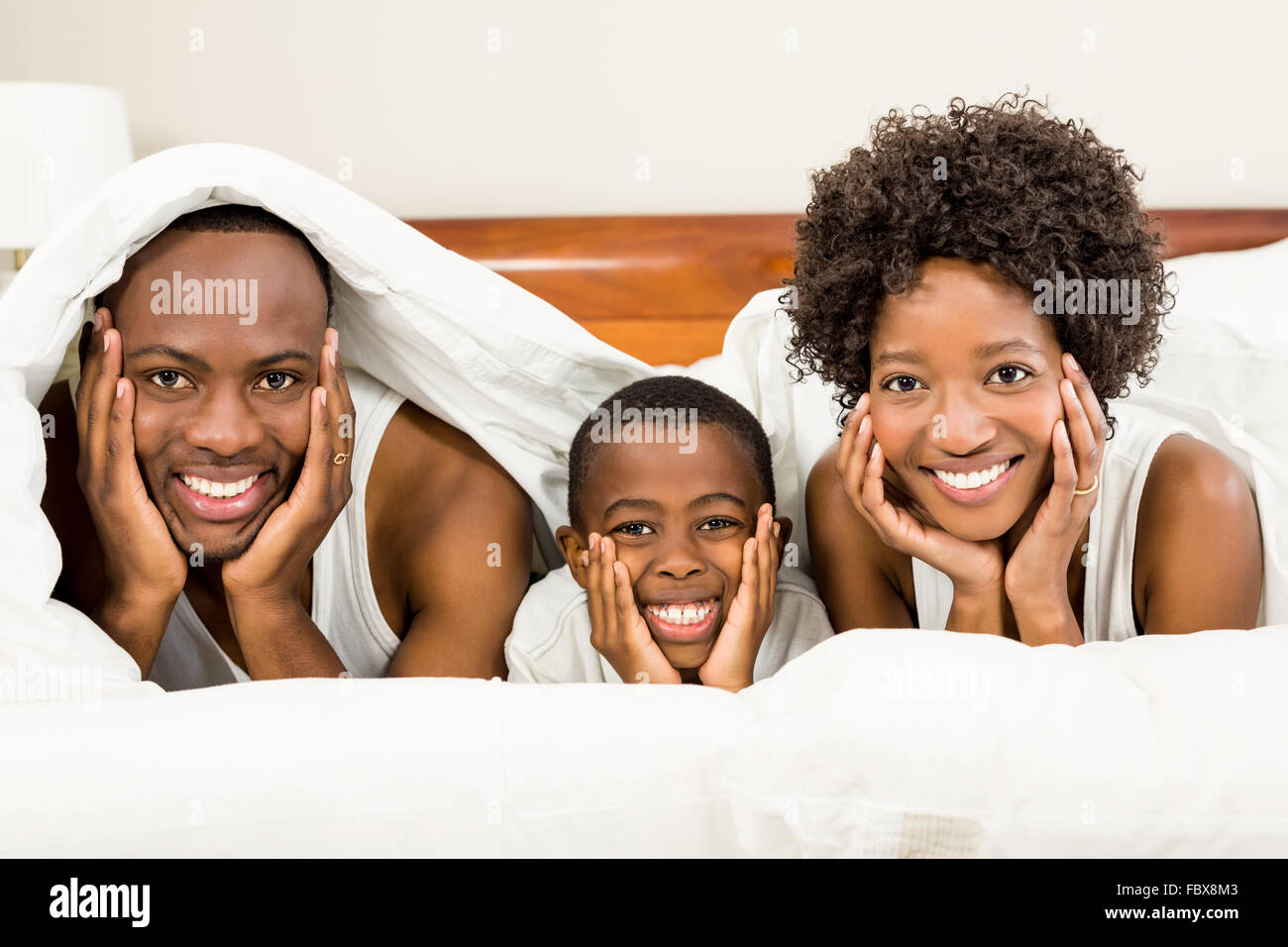 Happy family posing in bed under blanket Stock Photo