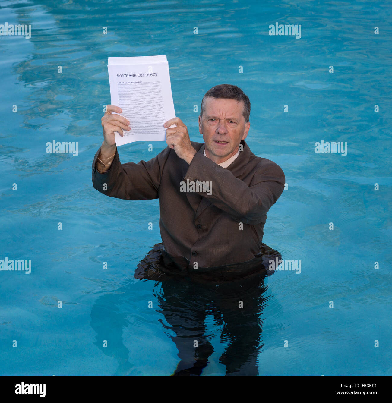 Senior man holding mortgage loan document in water Stock Photo