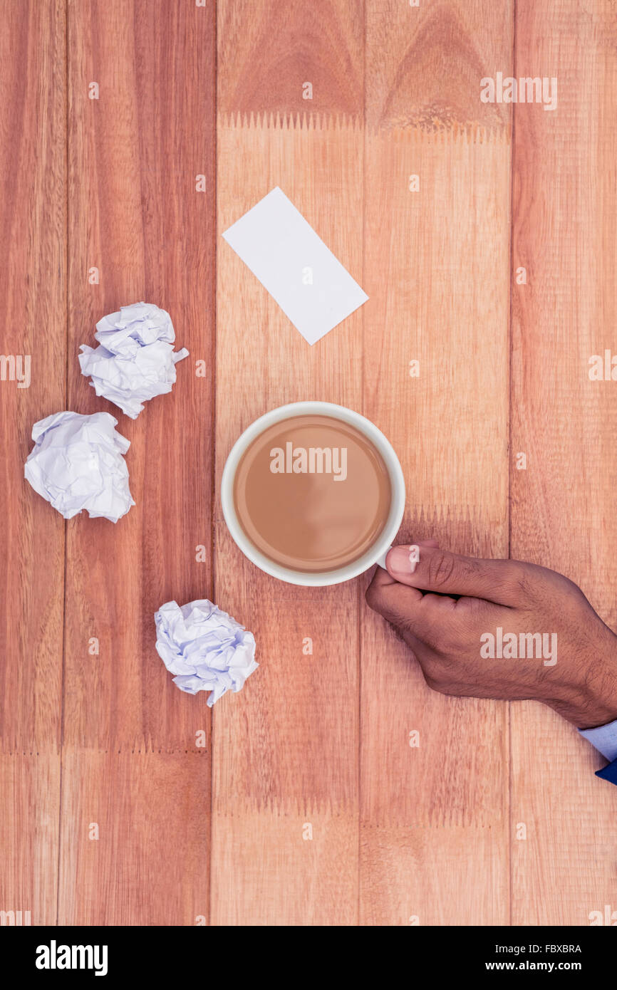 Styrofoam coffee cup with plastic spoon and used creamer container in  foreground and human elbows on table in background. Stock Photo