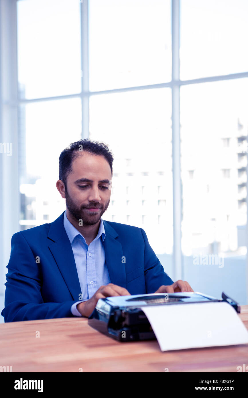 Businessman working on typewriter while sitting at desk in office Stock Photo