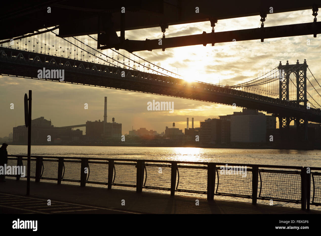 The sun rises under the Manhattan Bridge spanning the East River joining Manhattan to DUMBO, Brooklyn Stock Photo