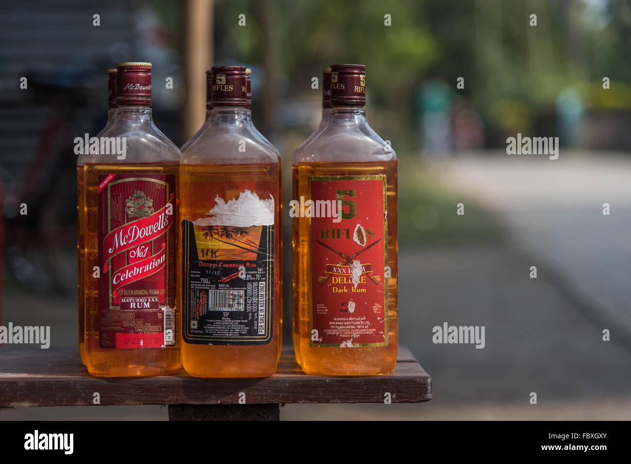 Shabby alcohol bottles that have been refilled with gasoline for sale. On a  bench outside the Balipara Saturday Market, Assam, India Stock Photo - Alamy