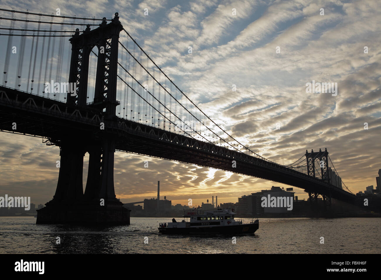 Sunrise over the Manhattan Bridge New York City with mackerel sky and industrial buildings on the horizon Stock Photo