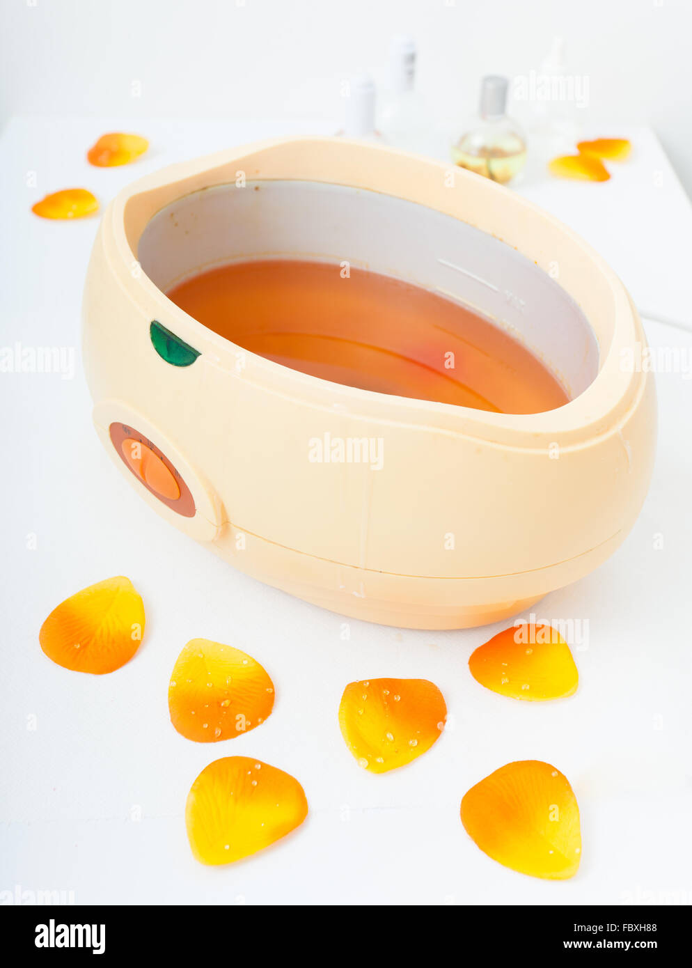 Orange parrafin wax in bowl. Manicure in beauty spa salon. Stock Photo