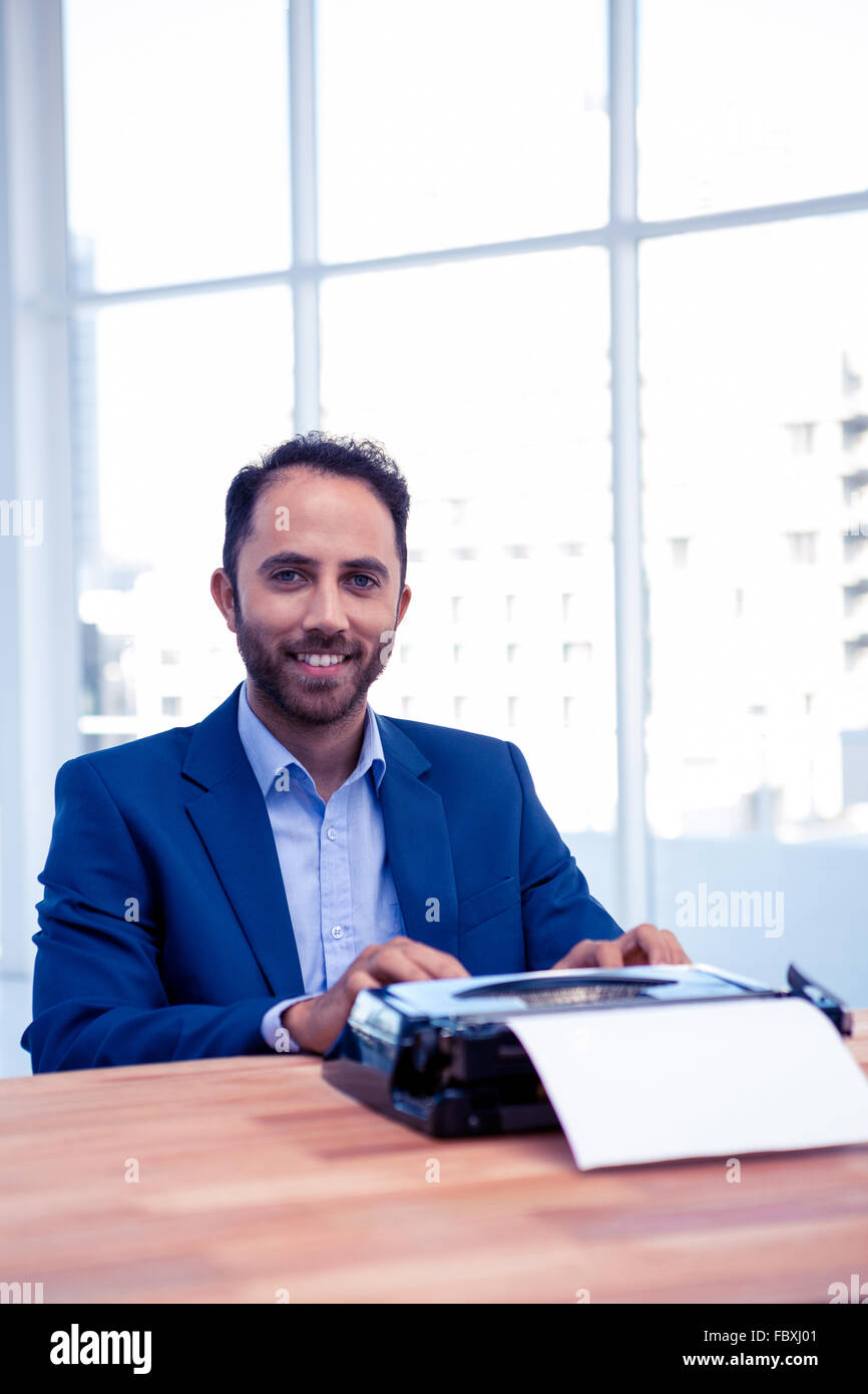 Portrait of smiling businessman working on typewriter  at office Stock Photo